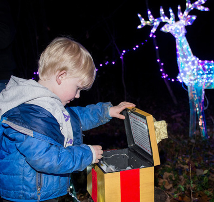 a child opening a box with a box in front of a reindeer