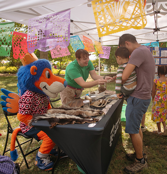People visiting a booth with the FC Cincinnati lion at the Hispanic heritage festival