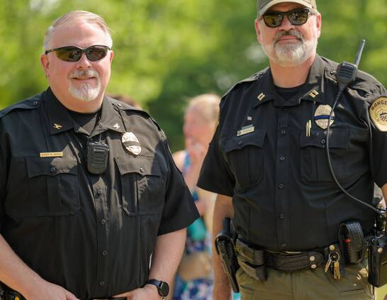 two rangers in their law enforcement uniforms standing in front of blurred trees