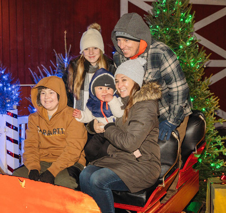 a group of people sitting on a sleigh with a christmas tree