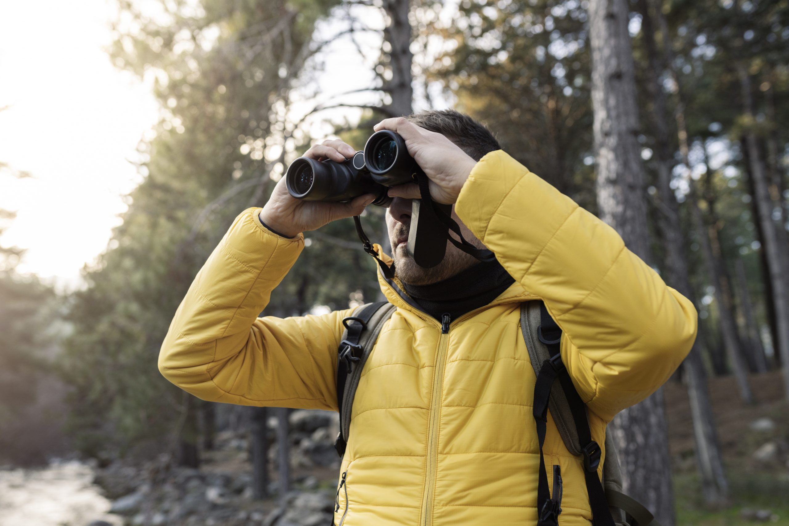 Man in nature looking through binoculars