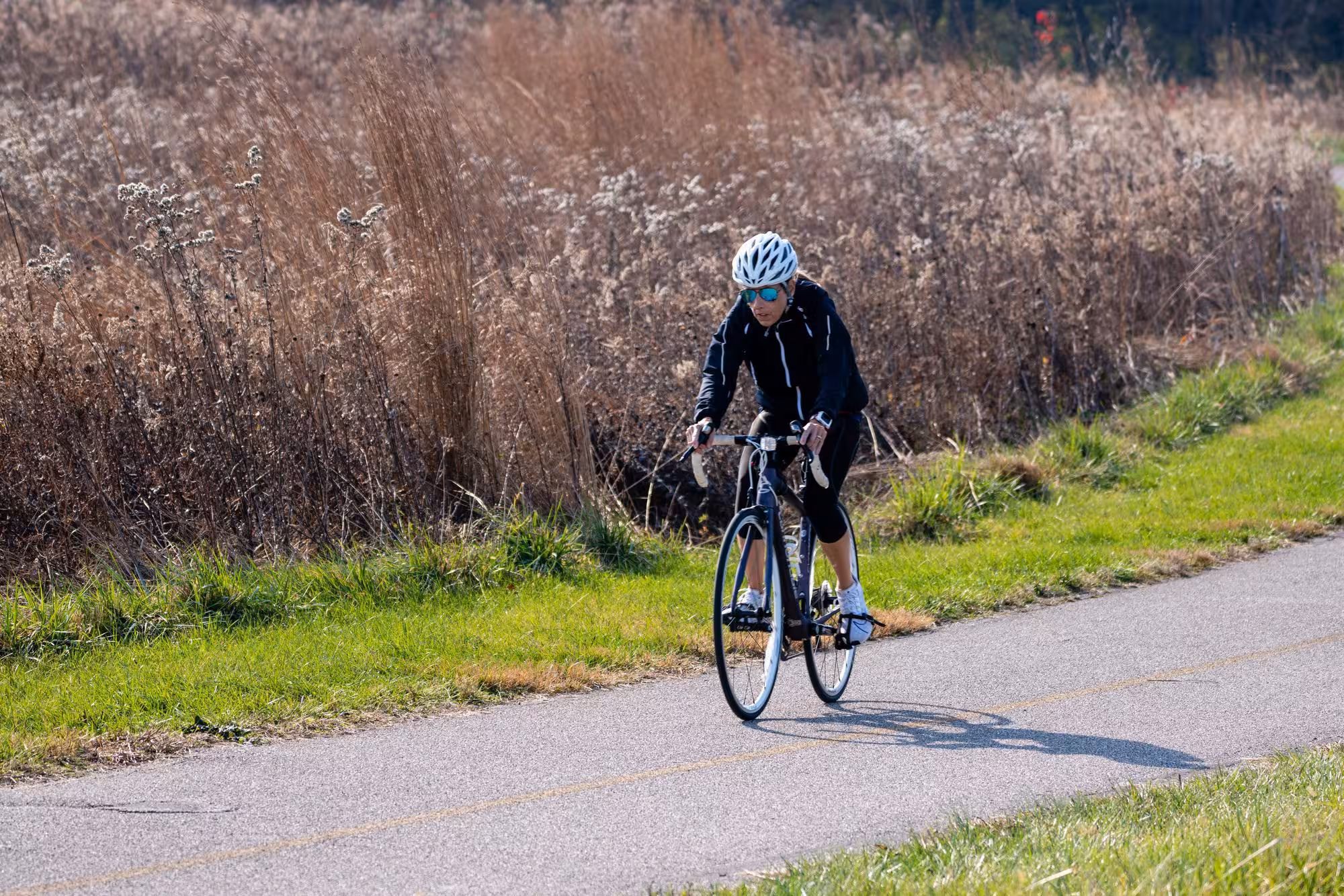 Cyclist on a paved trail next to a prairie