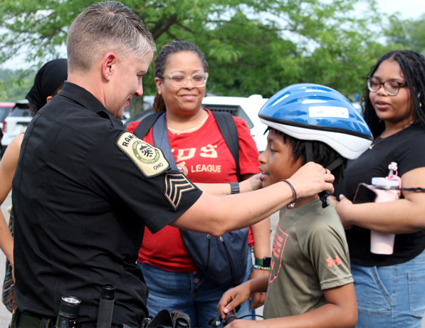 a police officer fixing a boy's helmet