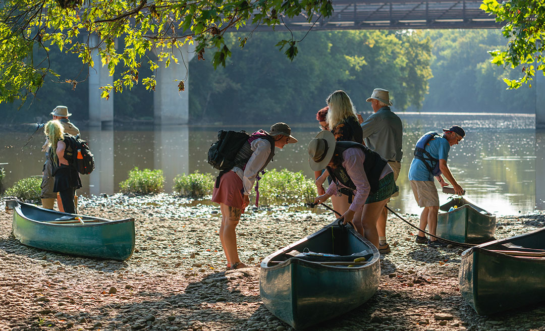 a group of people with backpacks and a canoe on a beach