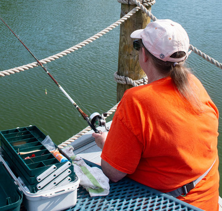 a woman in an orange shirt holding a fishing pole